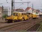 Gleisstopfmaschine, Schotterplaniermaschine und zwei Bauwagen der Bahnbau Gruppe fahren durch ...